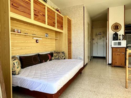une chambre avec un grand lit avec une tête de lit en bois dans l'établissement Argelès-sur-Mer : Studio cabine avec terrasse, proche plage et commerces, parfait pour famille - FR-1-225-637, à Argelès-sur-Mer