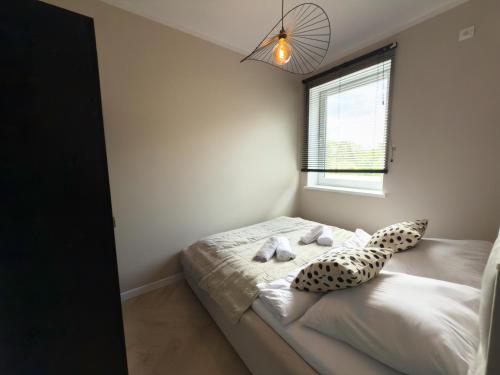 a bedroom with a bed with two pillows and a window at Apartamenty przy Dworcu by LibertaRent in Wałbrzych