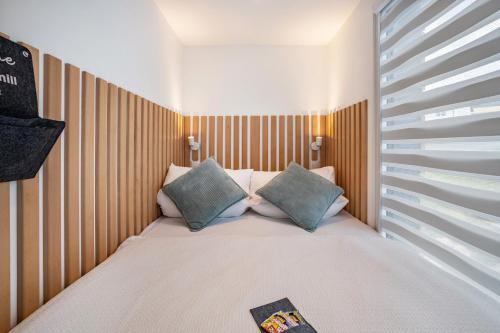 a small bedroom with a bed with two pillows at Tinyhaus Supreme für 1-4 Personen in Fuchsmühl