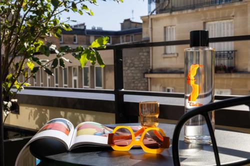 a table with a book and a pair of glasses and a water bottle at Belinda Hôtel & Spa in Paris