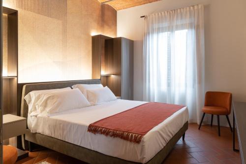 a bedroom with a bed with a window and a chair at Borgo Bucciano in San Miniato