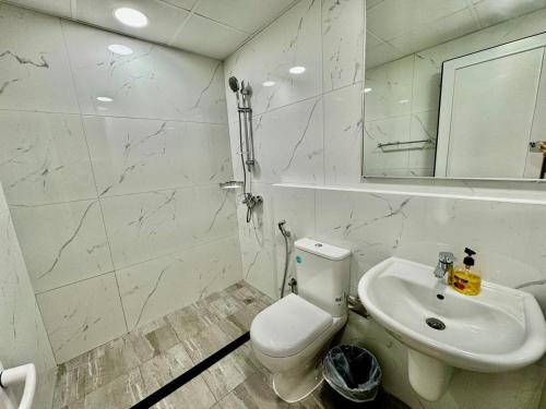 a white bathroom with a toilet and a sink at Spacious unit with a terrace in Dubai