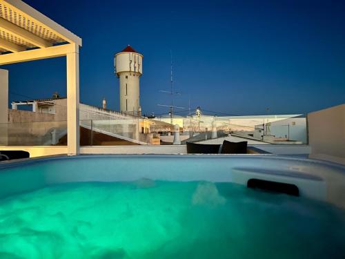 a swimming pool with a lighthouse in the background at Casa da Praça - Vila do Bispo, Algarve in Vila do Bispo