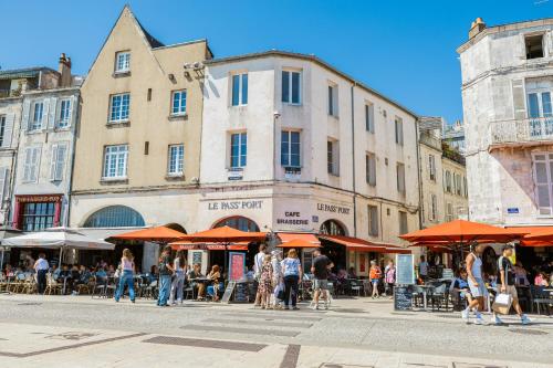 un groupe de personnes se promenant dans une rue avec des parapluies dans l'établissement Appartement chic vue imprenable sur le vieux port, à La Rochelle