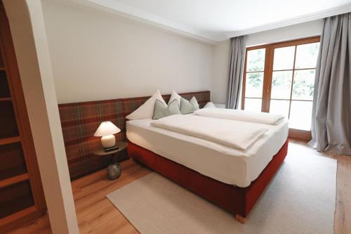 a bedroom with a bed with white sheets and a window at Alpenschlössl Boutique Appartements & Rooms in Neustift im Stubaital