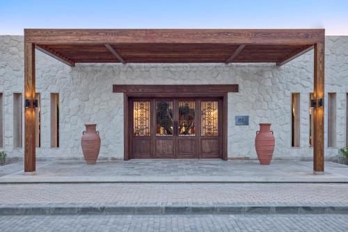 a building with vases in front of a wooden door at JAZ Almaza BLU, Almaza Bay in Marsa Matruh