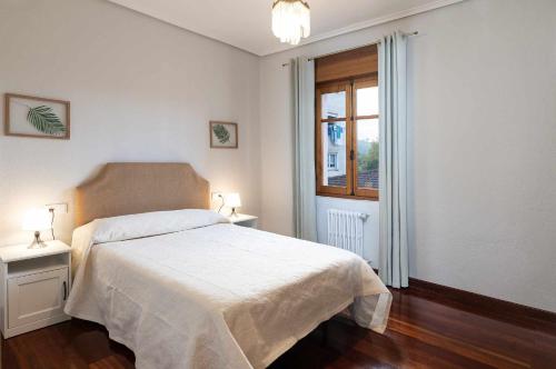 a bedroom with a white bed and a window at Apartamento La Vega de Santiago 2 in Posada de Llanes