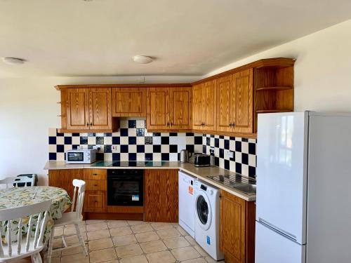 a kitchen with wooden cabinets and a white refrigerator at 4 Peak Apartment - Sea View in Bundoran