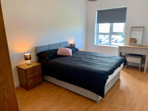 Un dormitorio con una cama y un escritorio y una ventana. en 4 Peak Apartment - Sea View, en Bundoran