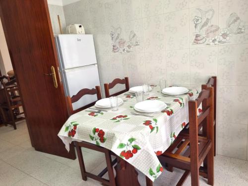 a kitchen table with a tablecloth with plates and a refrigerator at CASA DO SOL by Stay in Alentejo in Vila Nova de Milfontes