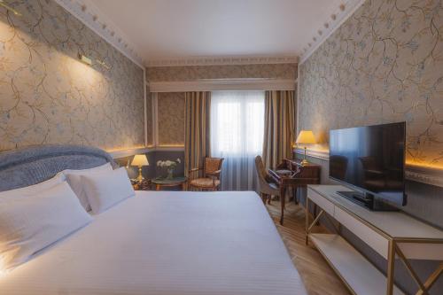 a hotel room with a bed and a flat screen tv at Mediterranean Palace in Thessaloniki