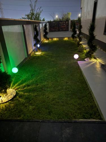 a backyard with lights on the grass at night at Vila luxury chiajna in Chiajna