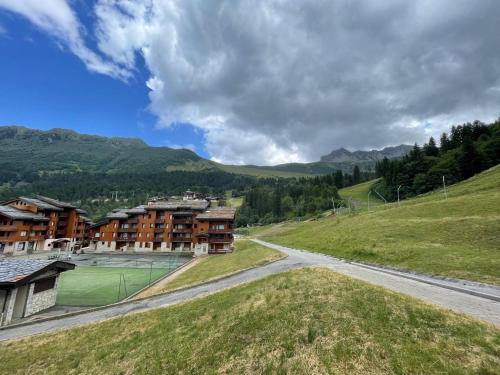 un chemin de terre dans un champ à côté de quelques bâtiments dans l'établissement Studio cosy près des pistes à Valmorel, animaux admis - FR-1-356-349, à Valmorel