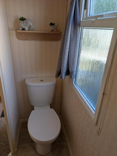 a small bathroom with a toilet and a window at 21 Chestnut Grove in Kirkcolm