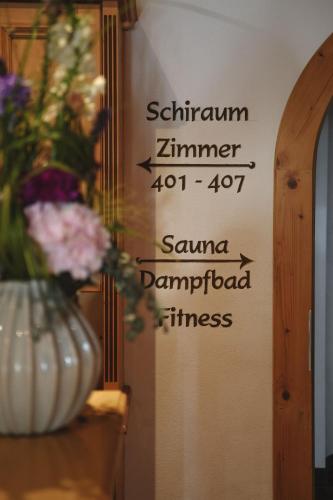 a sign on a wall with a vase of flowers at Alpenschlössl Boutique Appartements & Rooms in Neustift im Stubaital