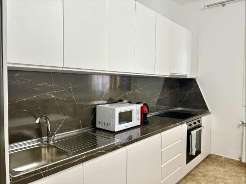 a kitchen with white cabinets and a microwave at Ishëm Greenview Apartments in Draçi
