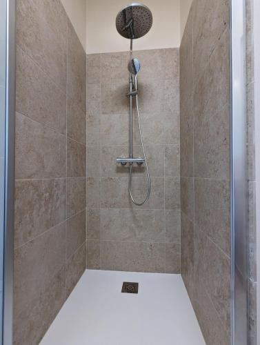 a shower with a shower head in a bathroom at Maison Prunier in Jarnac