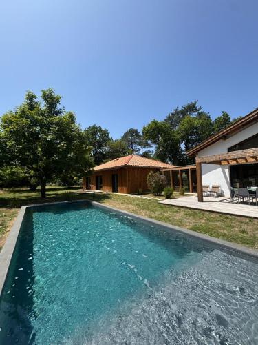 une piscine devant une maison dans l'établissement Villa des Résiniers piscine, proche plage & forêt, à Moliets-et-Maa