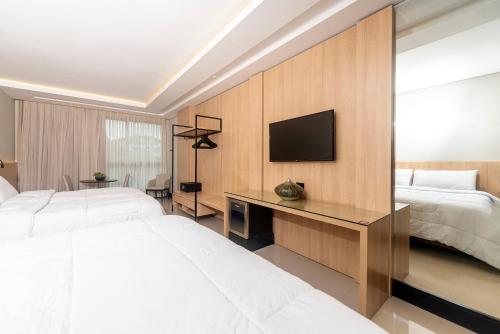 a bedroom with two beds and a desk with a television at Rafain Palace Hotel & Convention Center in Foz do Iguaçu