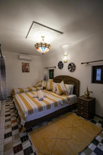 a bedroom with a large bed and a chandelier at Riad Dar Jnan Sbil in Fès