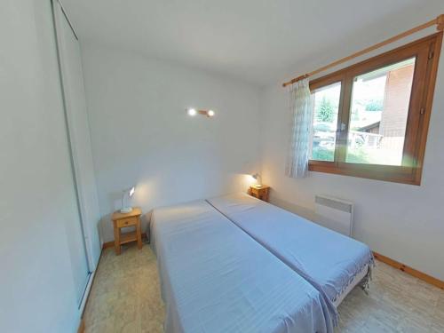 une chambre avec un grand lit avec une fenêtre dans l'établissement Appartement 2 Pièces Cabine avec Balcon Sud - Proche Pistes et Commerces - FR-1-241-188, au Grand-Bornand