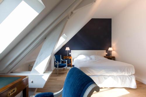 een slaapkamer met een wit bed en een blauwe stoel bij Les vignes blanches in Beaune