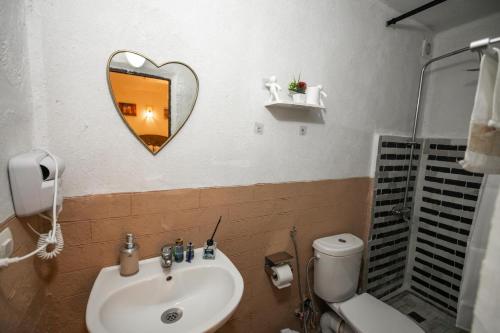a bathroom with a sink and a heart shaped mirror at Riad Dar Jnan Sbil in Fès