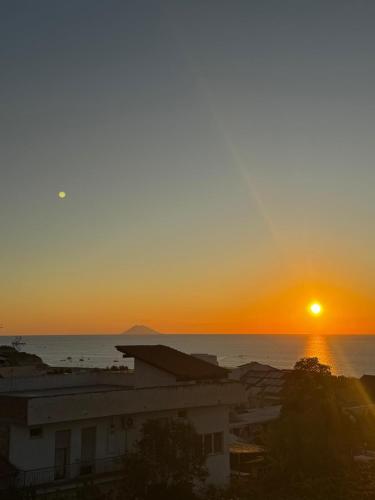 a sunset over the ocean with a building at Case Vacanze Giardino in Parghelia