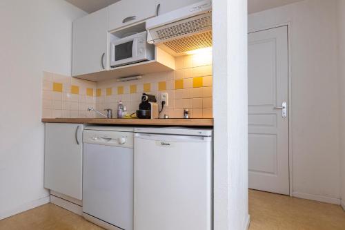 a kitchen with white cabinets and a microwave at Résidence Odalys Soleil d'Aure in Saint-Lary-Soulan