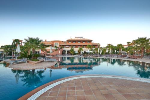 a swimming pool in a resort with palm trees and a building at Monte Santo Resort in Carvoeiro