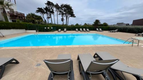 une grande piscine avec des chaises et une table dans l'établissement Trestraou 217, à Perros-Guirec