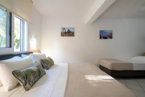 a white bedroom with a bed and a window at Palma Village by Greek Pride Hotels in Skála Foúrkas