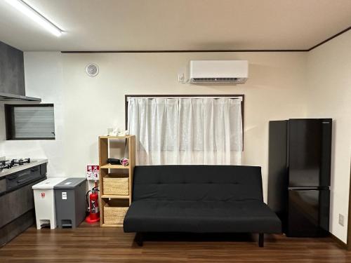 a living room with a black couch and a kitchen at Asakusa Riverside Family Inn in Tokyo