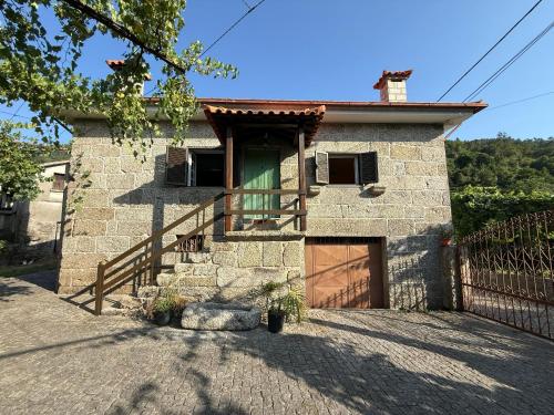 a stone house with a wooden door and a gate at Casa dos Patricios in Terras de Bouro