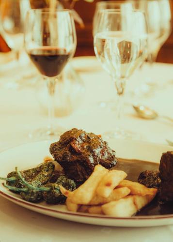 a plate of food on a table with glasses of wine at Hotel Conde Ansúrez in Valladolid