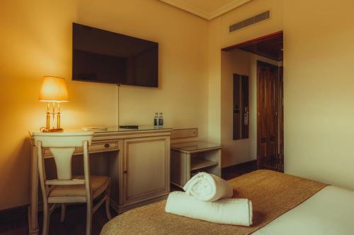 a hotel room with a bed with a desk and a television at Hotel Conde Ansúrez in Valladolid