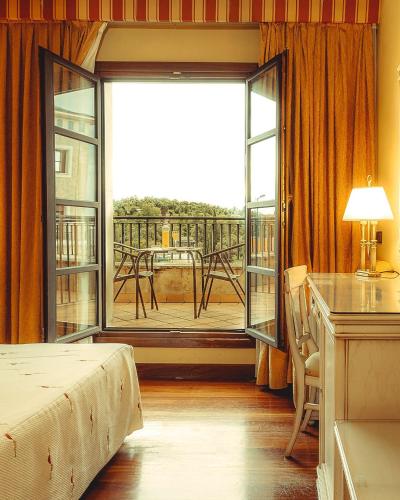 a bedroom with a bed and a large window with a balcony at Hotel Conde Ansúrez in Valladolid