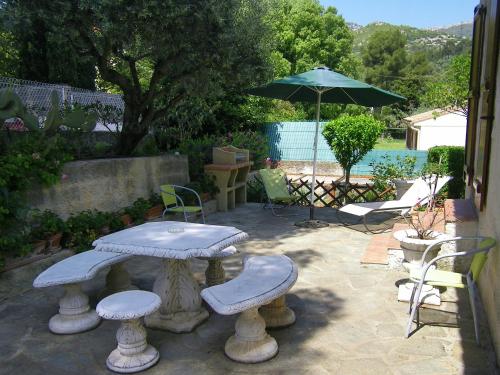 un patio avec une table, des chaises et un parasol dans l'établissement L'arche en rez de jardin de villa à Toulon, à Toulon