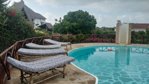a swimming pool with two chairs next to a swimming pool at Njala House - Villa con piscina in Watamu