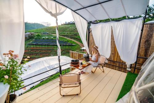 a woman sitting on a deck looking out at a vineyard at ภูวินคาเฟ่ โฮมสเตย์ Phuwin Homestay Monjam in Mon Jam