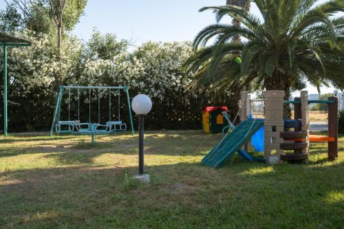 a playground with a palm tree and a swing at Palma Village by Greek Pride Hotels in Skála Foúrkas