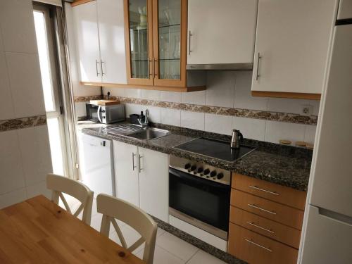 a kitchen with white cabinets and a sink and a table at Apto Carballo - NETFLIX y calefacción in Carballo
