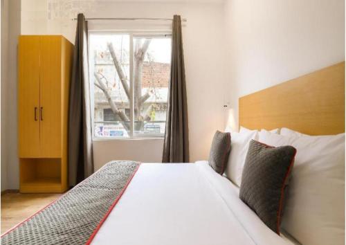 a bedroom with a large white bed with a window at Hotel Kingston House - Near Shaheed Path and Ayodhya Road in Lucknow