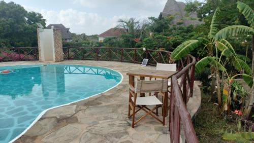 a table and a chair next to a swimming pool at Njala House - Villa con piscina in Watamu