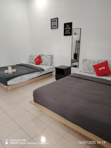 two beds with red pillows in a bedroom at Laman Hanaz in Pantai Cenang