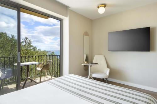 a bedroom with a bed and a balcony with a flat screen tv at Barceló Illetas Albatros - Adults Only in Illetas