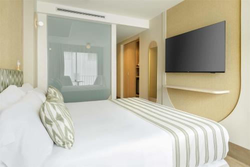 a bedroom with a white bed with a flat screen tv at Barceló Illetas Albatros - Adults Only in Illetas