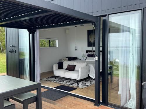 a living room with a white couch and a table at Kauri Lodge -Luxury waterfront in Pouto