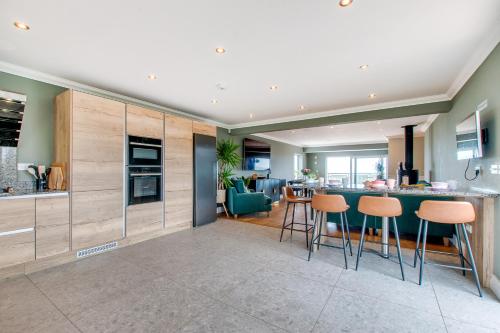 a kitchen with a counter and stools in a room at Botany Bay Beach House - Stunning Sea Views in Kingsgate