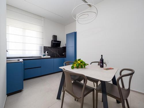 a kitchen with blue cabinets and a table with chairs at Blu Sky Luxury Palace Sorrento Coast in Meta